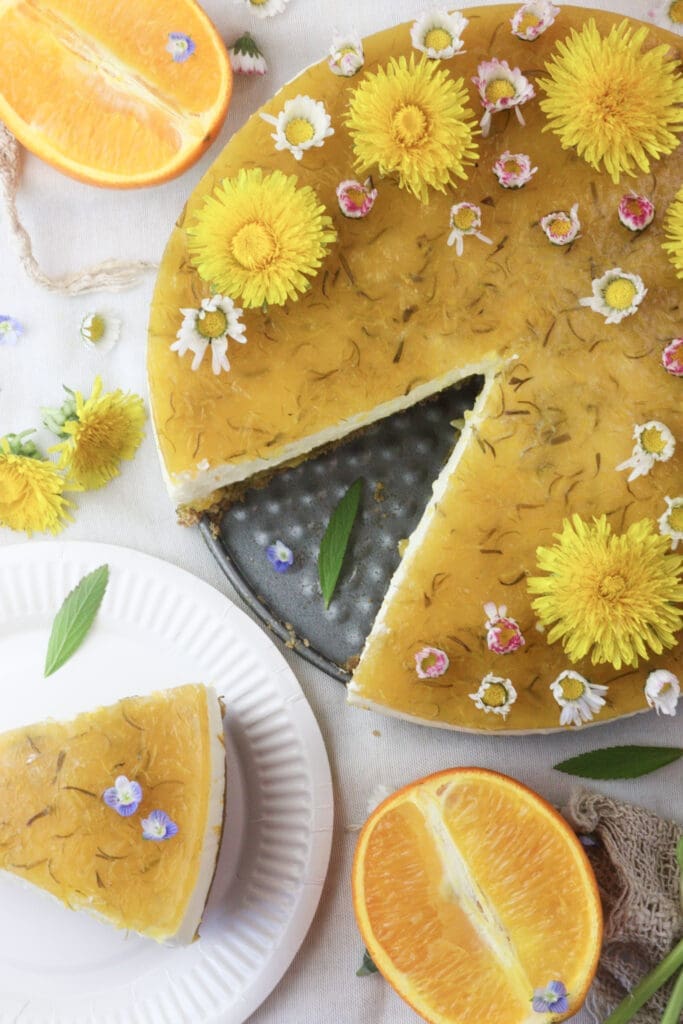 image of served and sliced orange dandelion cake with dandelion flowers, daisies and oranges